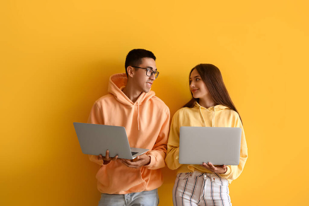 Jeune couple avec des ordinateurs portables sur fond jaune - Photo, image