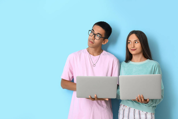 Junges Paar mit Laptops auf blauem Hintergrund - Foto, Bild