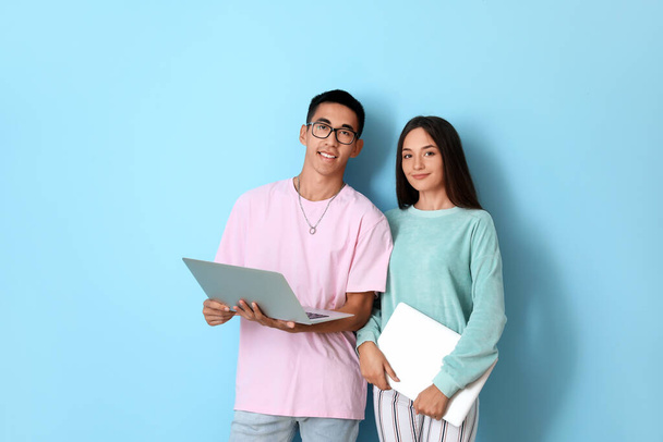 Jeune couple avec des ordinateurs portables sur fond bleu - Photo, image