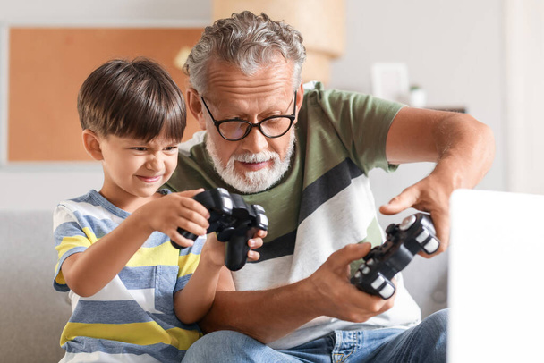 Μικρό αγόρι με τον παππού του να παίζει βιντεοπαιχνίδι στο σπίτι - Φωτογραφία, εικόνα