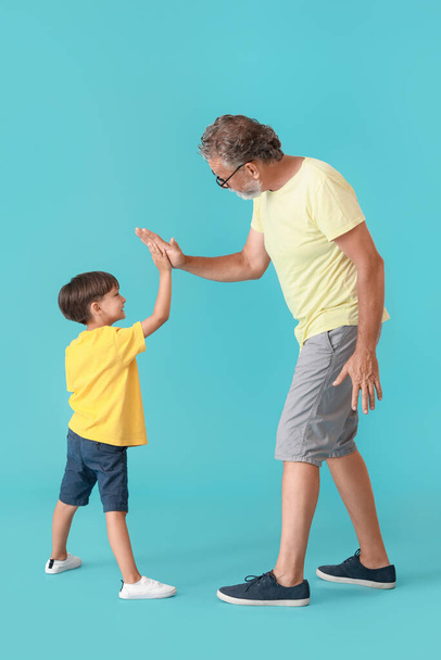 A kisfiú pacsit ad a nagyapjának, kék alapon. - Fotó, kép