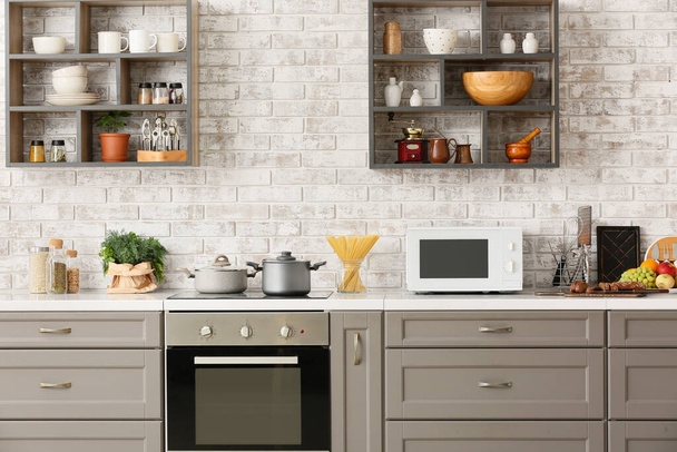Moderno horno de microondas en el mostrador cerca de la pared de ladrillo ligero en el interior de la cocina - Foto, imagen