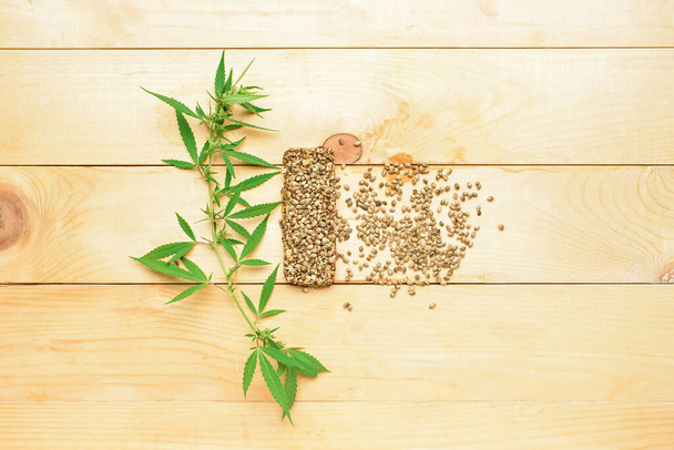 Barra de proteínas con semillas de cáñamo y arbusto sobre fondo de madera - Foto, imagen