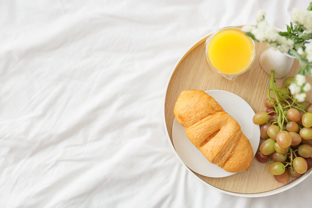 Tray with tasty breakfast and beautiful flowers on bed - Foto, Bild