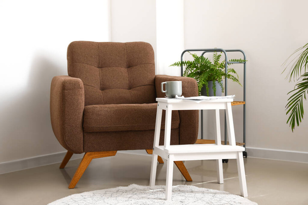 Acogedor sillón, taburete con taza y periódico en la sala de estar - Foto, imagen