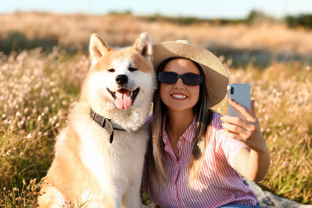 Mujer con divertido perro Akita Inu tomando selfie al aire libre - Foto, imagen