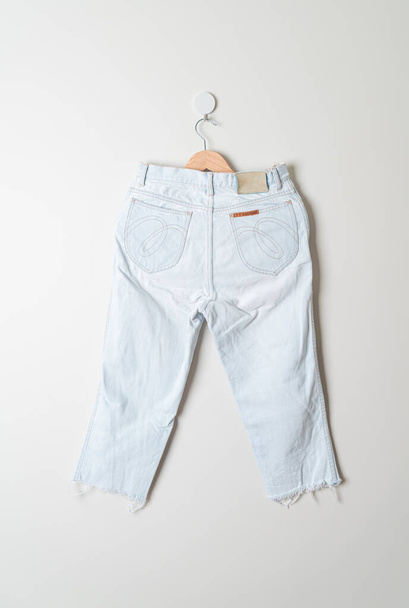 jeans trousers hanging with wood hanger on wall - 写真・画像
