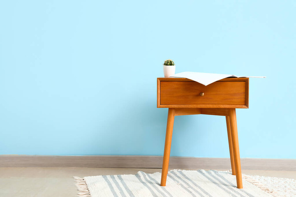 Table de chevet en bois avec plante d'intérieur sur fond mural bleu - Photo, image