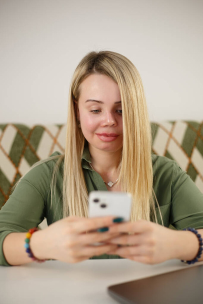Cheerful domestic abuse victim communicating online with new mobile phone. Good looking woman with facial scars and prosthetic eye using modern smartphone for online communication and entertainment - Zdjęcie, obraz