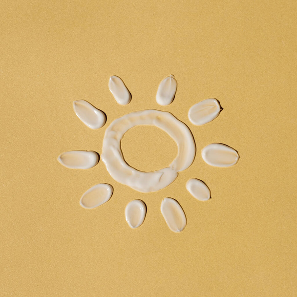 Güzellik ürünü. Güneş beyaz kozmetik krem lekesi, açık sarı arkaplan lekesi - Fotoğraf, Görsel