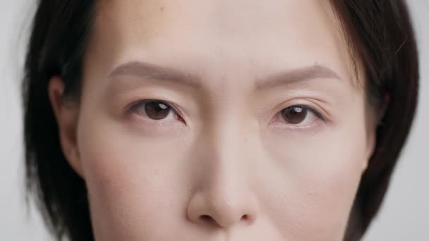 Recortado tiro de maduro coreano mujer cara sobre gris fondo - Imágenes, Vídeo