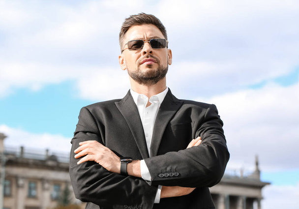 Stylish businessman in sunglasses on city square - Фото, зображення