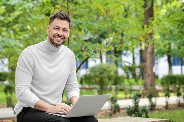 Stílusos üzletember dolgozik laptop padon a parkban - Fotó, kép