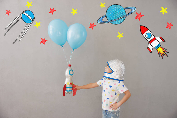 Happy child playing with toy rocket at home. Kid pretend to be astronaut. Imagination and children dream concept - Φωτογραφία, εικόνα