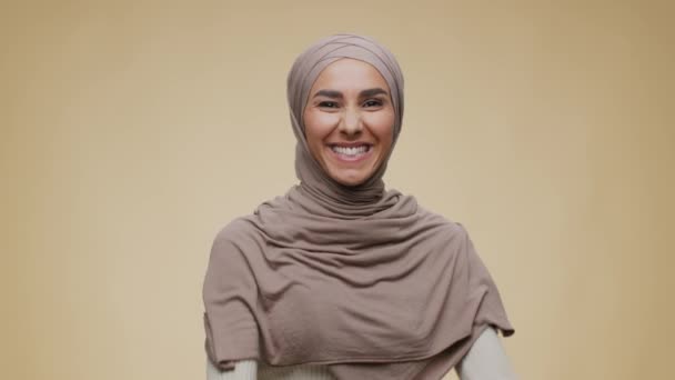 Vittoria ed eccitazione. Studio ritratto di giovane emotivo felice signora del Medio Oriente in hijab gesticolando SI e ballando - Filmati, video