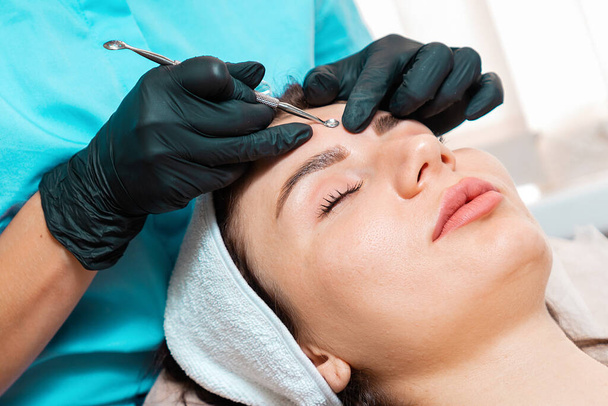 Salon cleansing beauty procedure. Cosmetologist in spa doing acne treatment using mechanical instrument. Close up of face. Concept of professional skin care. - Photo, Image