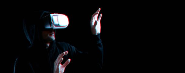 Vr Brille Virtual Reality gebläut. Junger Mann mit digitalem Helm für 3D-Virtual-Reality-Spiel auf dunklem Hintergrund. Studie und virtuelle Welt in 3D-Simulation mit Glitch-Effekt - Foto, Bild