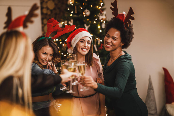 Quatre jolies filles multietnic s'amusent tout en trinquant avec du champagne à Noël ou à la fête du Nouvel An. - Photo, image