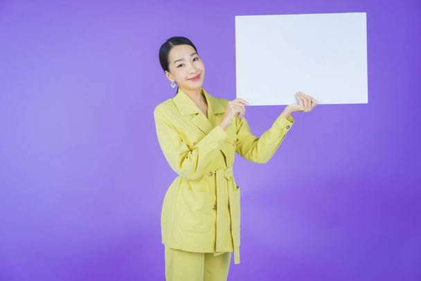 Портрет красива молода азіатка з порожнім білим рекламним щитом на кольоровому фоні
 - Фото, зображення
