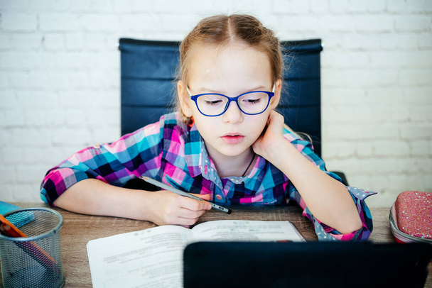 Malá holka v brýlích studuje on-line doma, základní škola dívka s počítačem s zoom video chat s učitelem - Fotografie, Obrázek