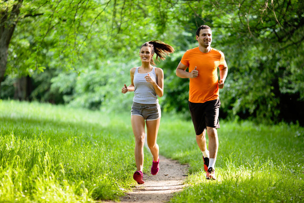Portrait of happy young fit people running together outdoors. Couple sport healthy lifestyle concept - Fotoğraf, Görsel