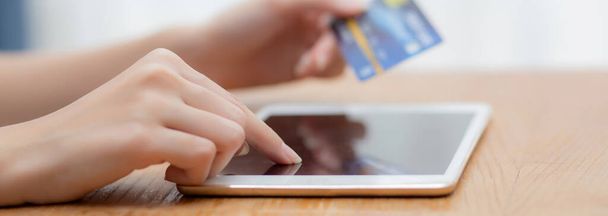Closeup χέρι της νεαρής ασιάτισσας που κατέχουν πιστωτική κάρτα ψώνια σε απευθείας σύνδεση με τον υπολογιστή ταμπλέτα κενή οθόνη αγορά και πληρωμή, κορίτσι που χρησιμοποιούν την αγορά ή συναλλαγή χρεωστικής κάρτας, e-commerce έννοια. - Φωτογραφία, εικόνα