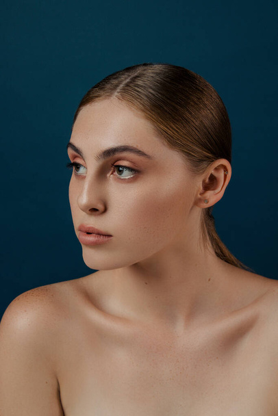 Young female, woman with clean perfect skin. Isolated girl in studio.  Fashion close up Portrait of beauty model with natural nude make up and long eyelashes. Blue solid background. - 写真・画像