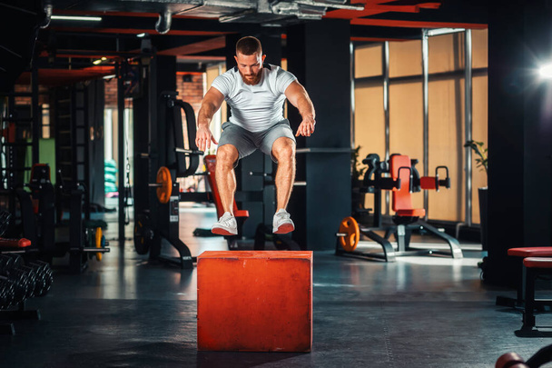 Giovane uomo atletico barbuto formazione in palestra saltando a cubo. Il concetto di fitness. - Foto, immagini