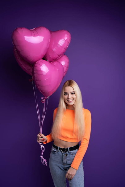Happy blonde with heart-shaped balloons on a purple background in the studio. Valentines Day February 14. - Foto, Imagem