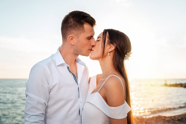 Jeune et beau couple embrassant de mari et de femme. En arrière-plan, l'océan et le coucher du soleil. Je viens de me marier. - Photo, image