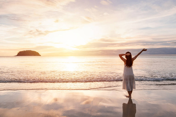 Young woman traveler walking and enjoying beautiful Sunset on the tranquil beach, Travel on summer vacation concept - Valokuva, kuva