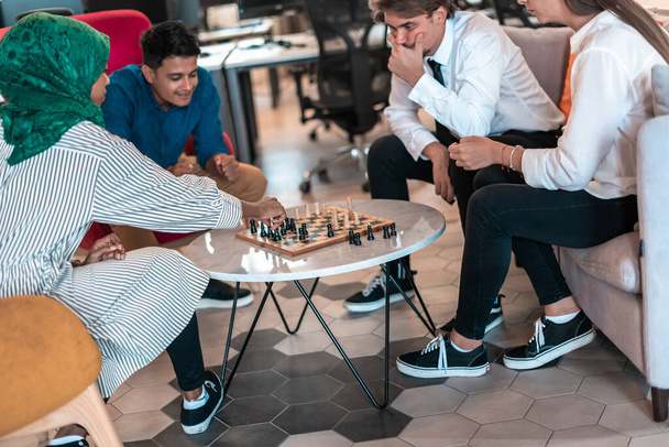 Multiethnic group of businesspeople playing chess while having a break in relaxation area at modern startup office. High-quality photo - Foto, immagini