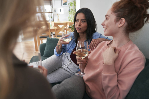 Three  female caucasian friends chatting and drinking wine at home - Foto, immagini