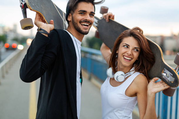 Portrét mladého páru s skateboardem a longboardem baví společně venku - Fotografie, Obrázek