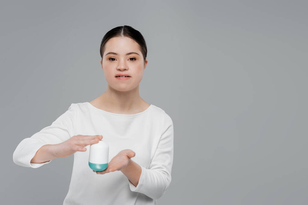Woman with down syndrome holding deodorant isolated on grey  - Fotó, kép