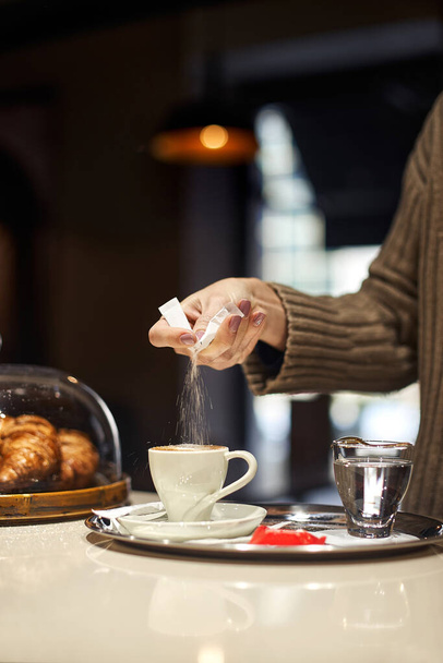 Female hand pours sugar into coffee. The concept of a break, rest in a cafe. Copyspace. - Foto, Imagen