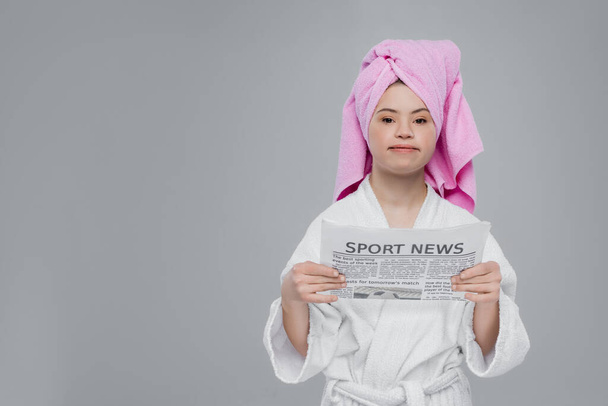 Vrouw met dons syndroom in badjas en handdoek houden krant geïsoleerd op grijs  - Foto, afbeelding