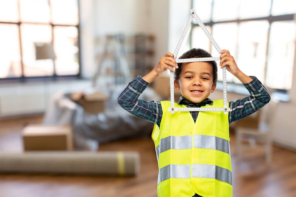 little boy in safety vest with house made of ruler - Foto, imagen