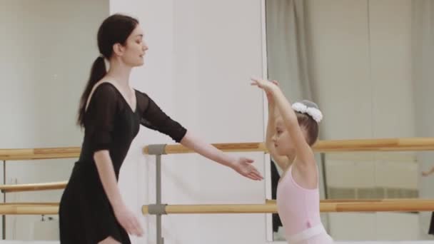 Обучение балету - маленькая девочка-балерина танцует в зеркальной студии и тренер наблюдает за ней - Кадры, видео