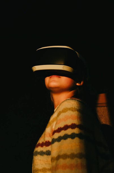 Futurisztikus felvétel egy VR szemüveges nőről, aki a fényes naplemente fényében áll. Erős kontraszt, erős fénylövés.. - Fotó, kép