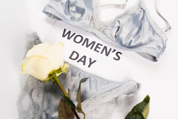 Top view of card with womens day lettering, rose and lingerie on white background  - Foto, immagini