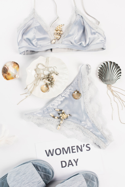 Top view of lace underwear near slippers, accessories and card with womens day lettering on white background  - Photo, Image