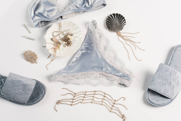 Top view of blue lingerie, slippers and accessories on white background  - Fotó, kép