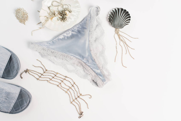 Top view of accessories, silk panties and slippers on white background  - Fotó, kép