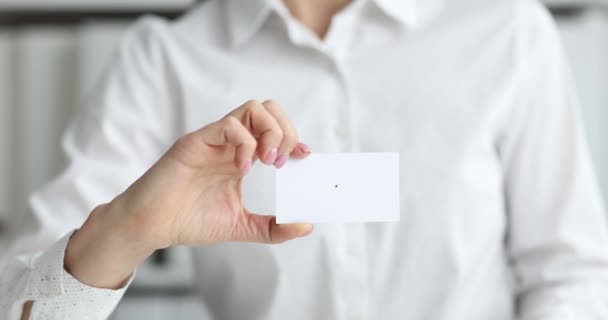 La mano femenina sostiene la tarjeta de visita en el primer plano del lugar de trabajo - Metraje, vídeo