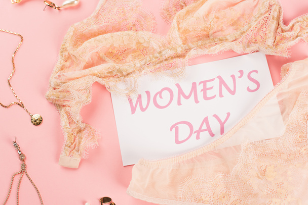 Top view of lingerie, card with womens day lettering and accessories on pink background  - Fotografie, Obrázek