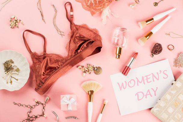 Top view of bra, card with womens day lettering, present and perfume on pink background  - Photo, Image