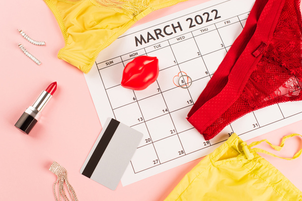 Top kilátás március naptár, fehérnemű és hitelkártya rózsaszín háttér  - Fotó, kép