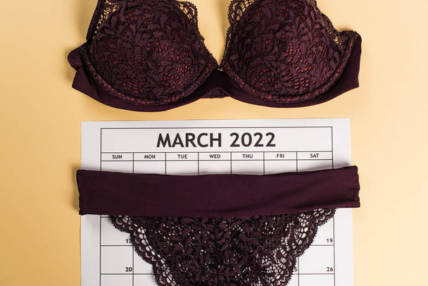Top view of lace lingerie on march calendar on beige background  - Photo, Image