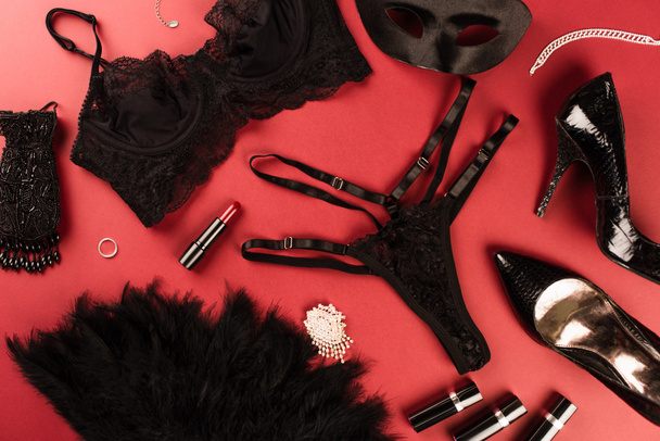 Top view of sexy lingerie, lipsticks and heels on red background  - Φωτογραφία, εικόνα